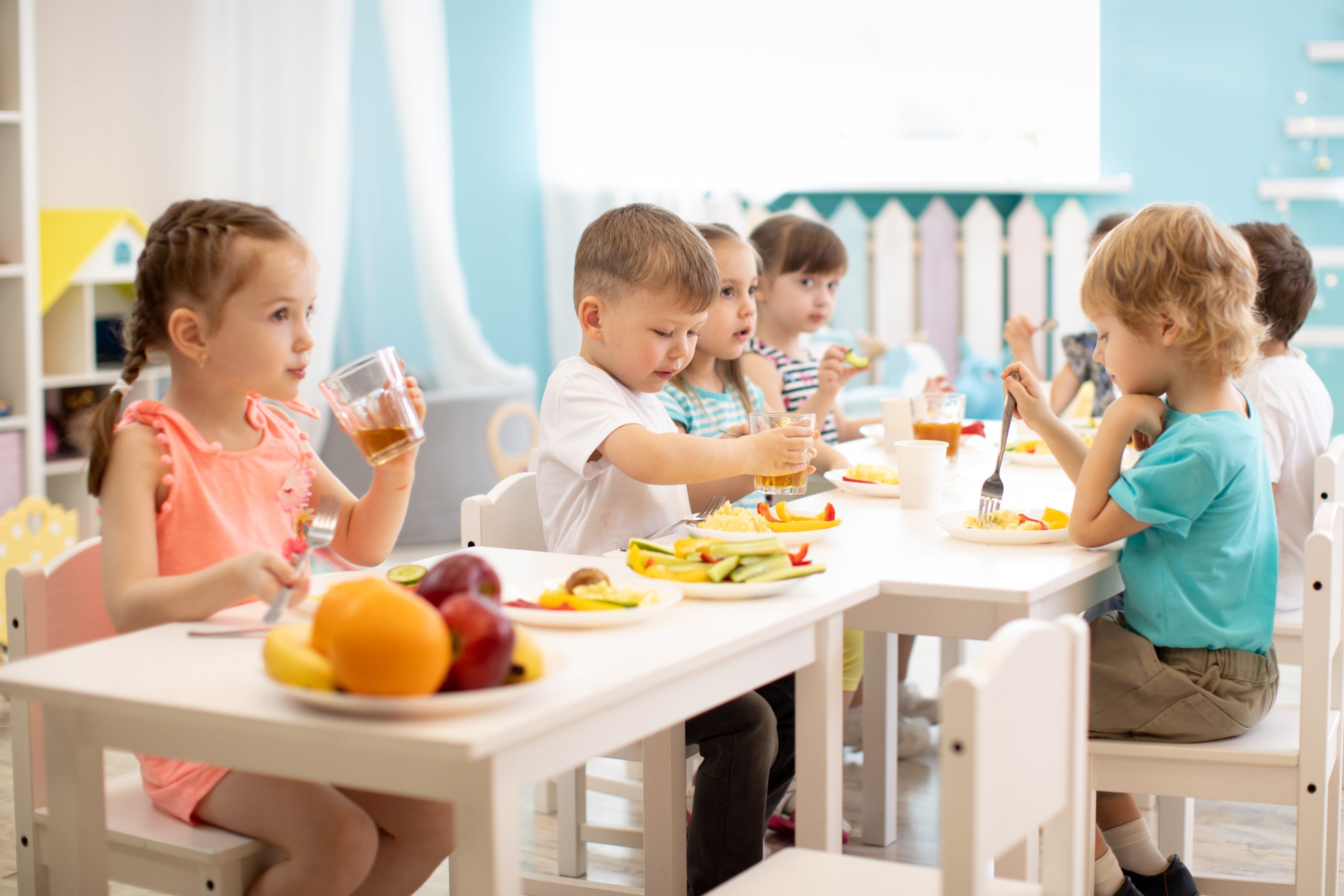 Group of children eating healthy food in day care centre
